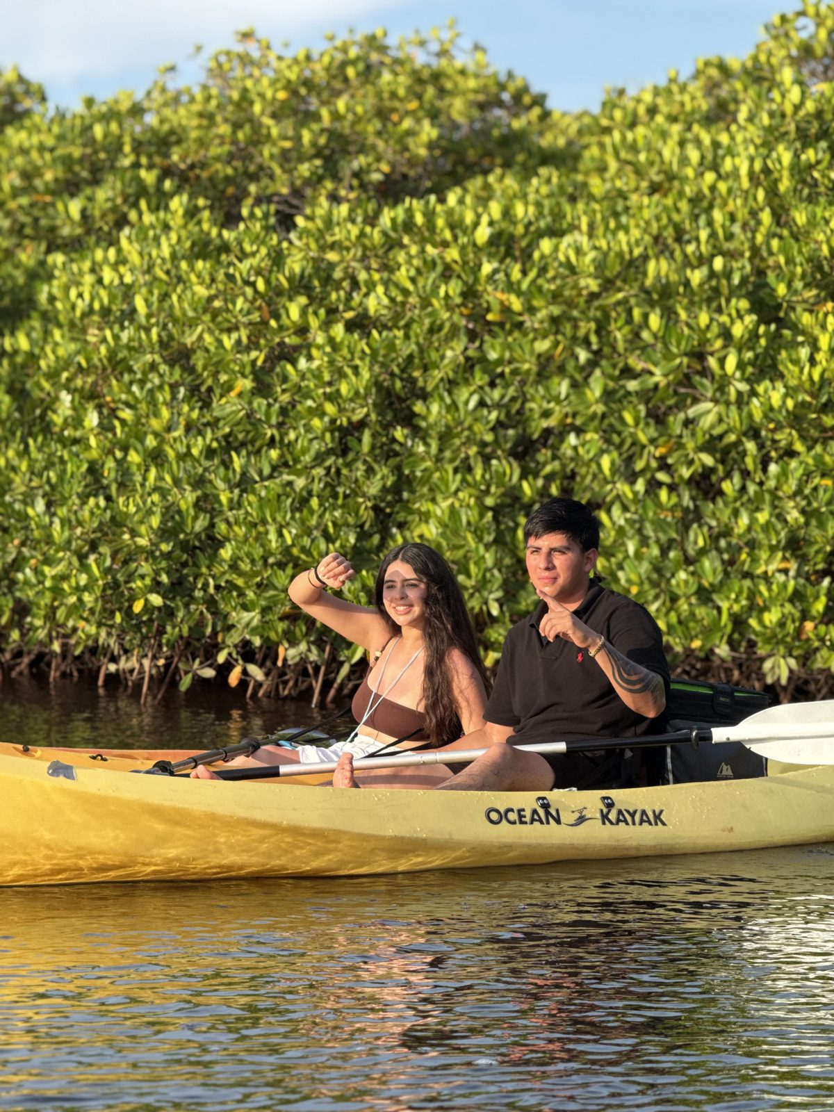 Pareja en un kayak amarillo sonriendo entre los manglares