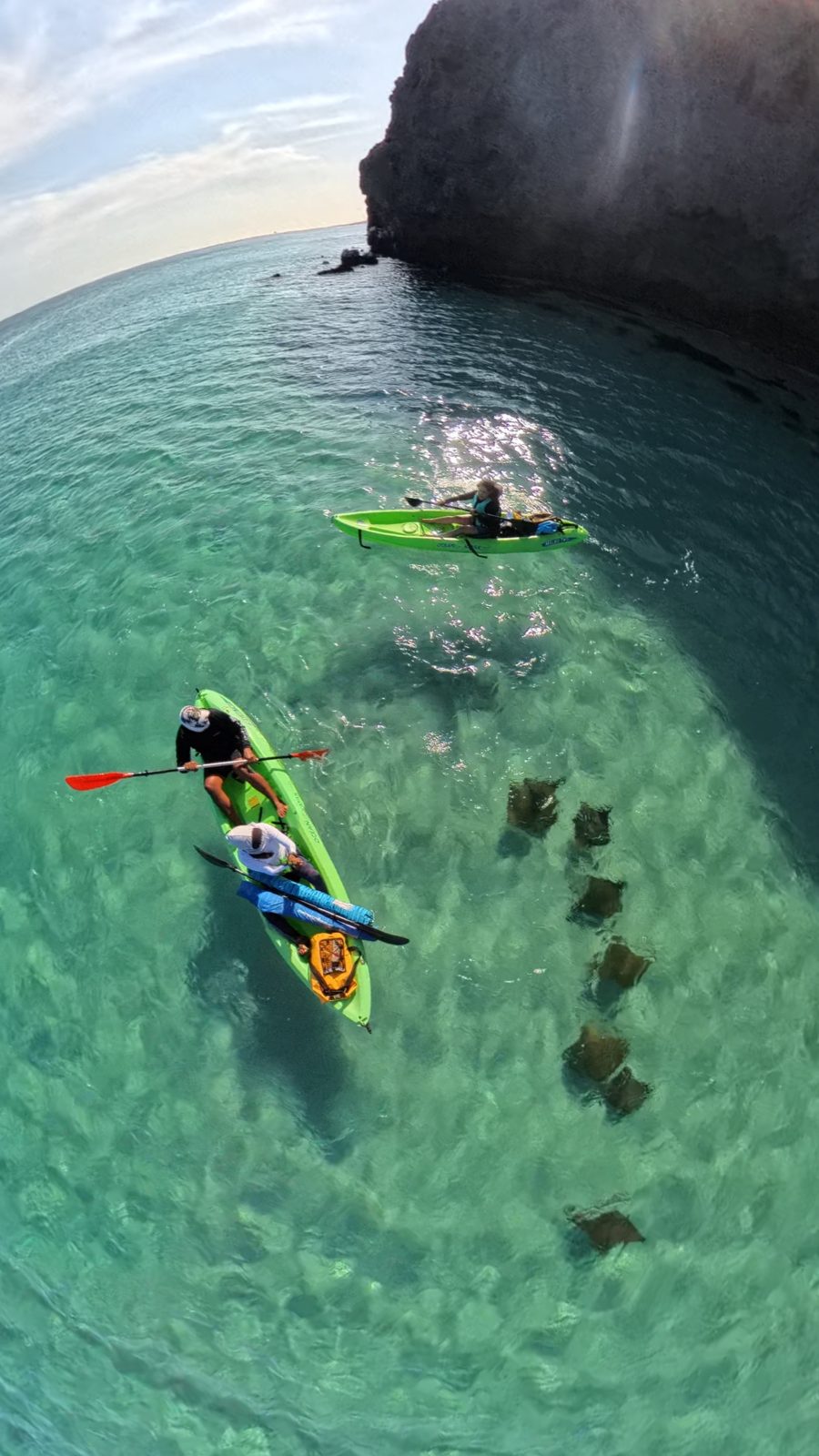 Kayak en el agua turquesa de Tecolote con el cerro al fondo y mantarrayas visibles
