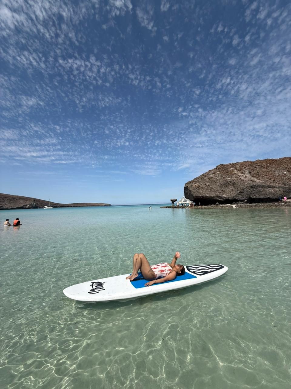 Paddleboarder descansando sobre la tabla en la bahía turquesa de La Paz