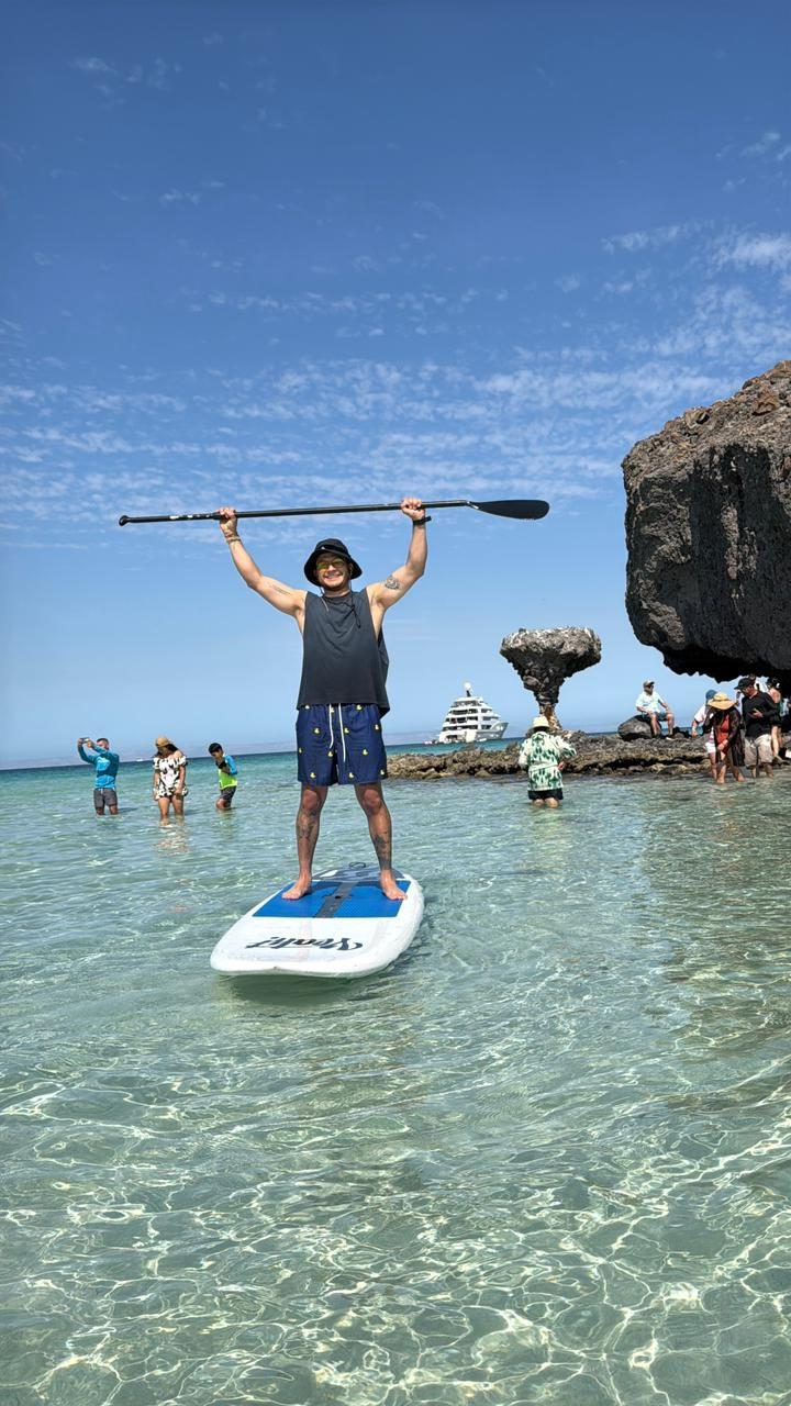 Paddleboarder con el remo en alto sobre el agua tranquila de la bahía