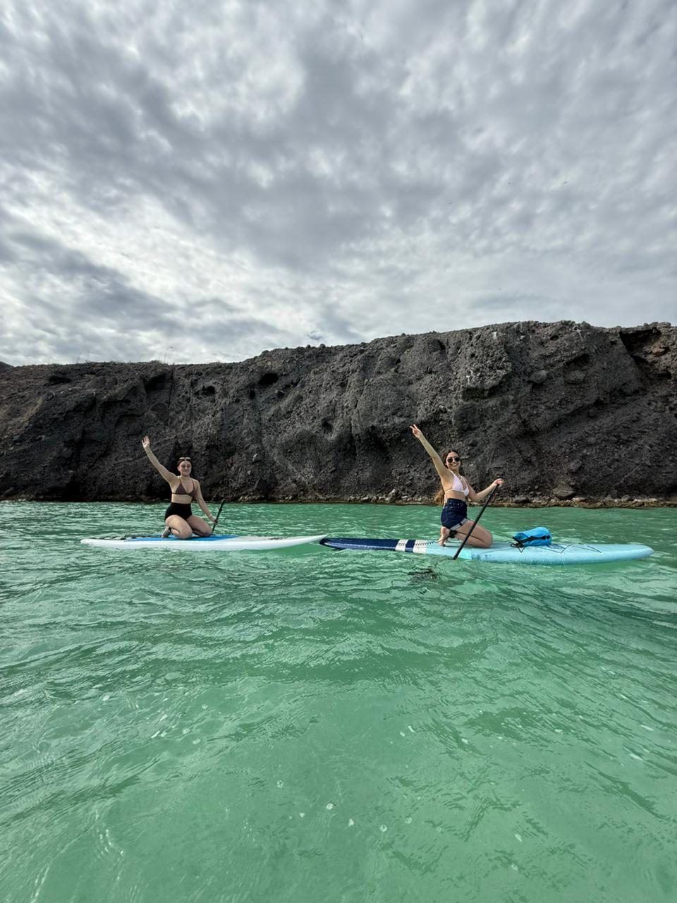 Dos personas celebrando de pie sobre paddleboards en la bahía de La Paz