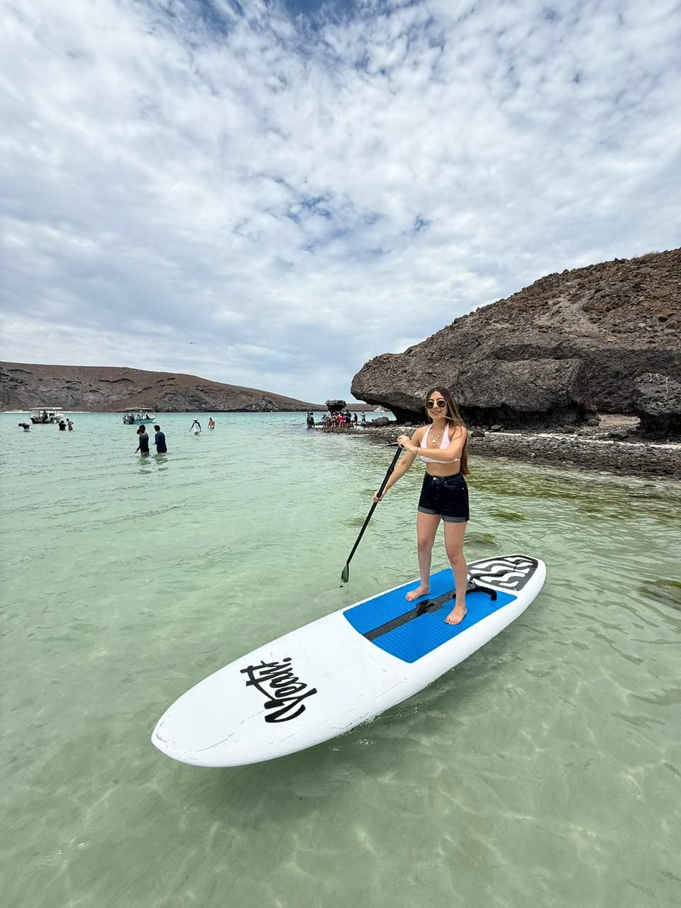 Paddleboarder de pie remando sobre una tabla azul en La Paz