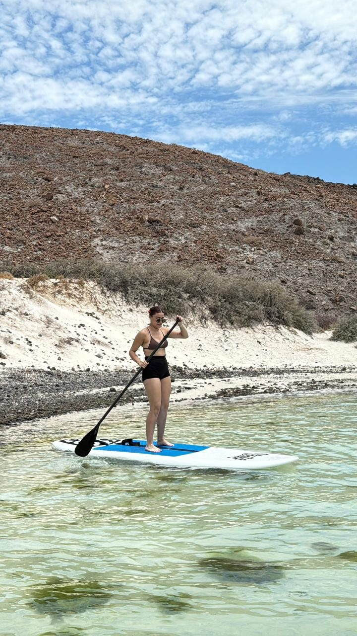 Paddleboarder sobre el agua cristalina con los cerros al fondo