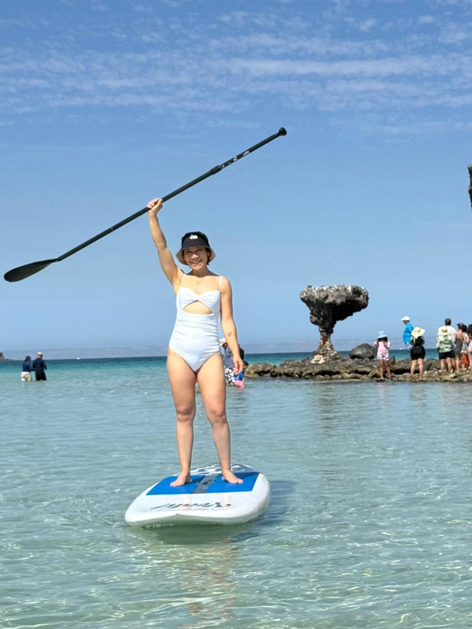 Paddleboarder de pie con el remo en alto en la playa de Tecolote