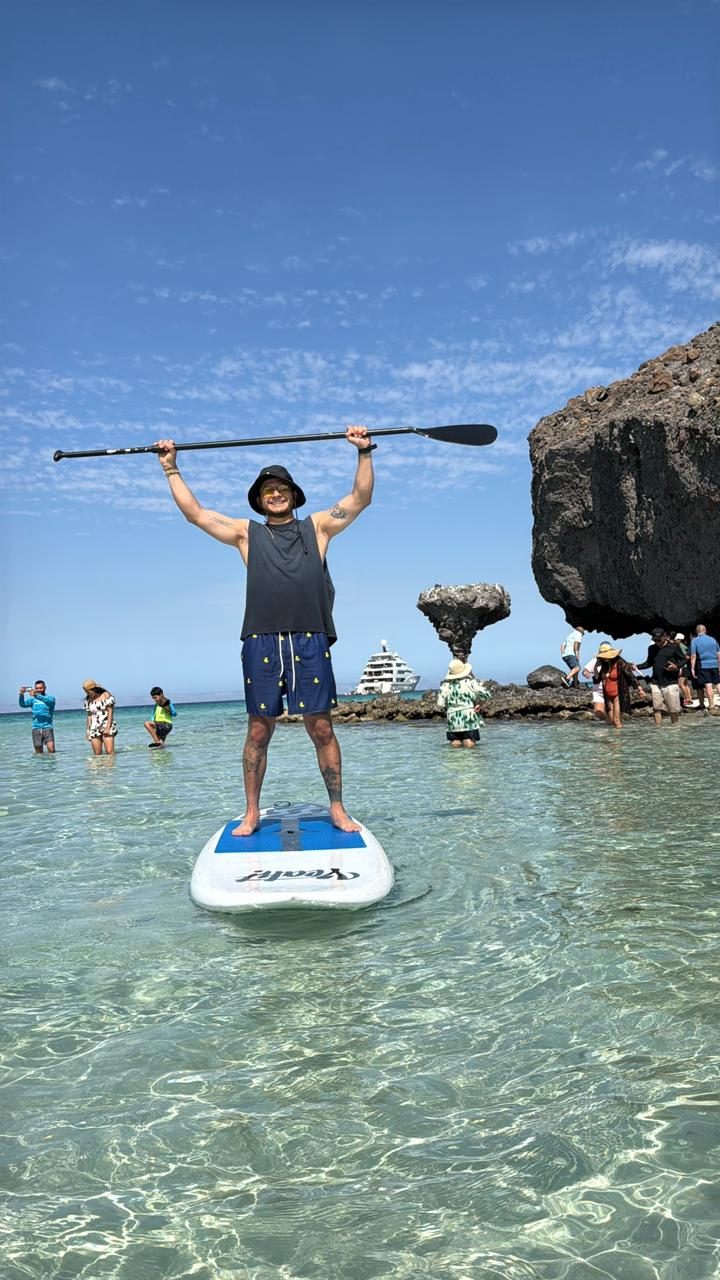 Paddleboarder celebrando con el remo en alto en Tecolote