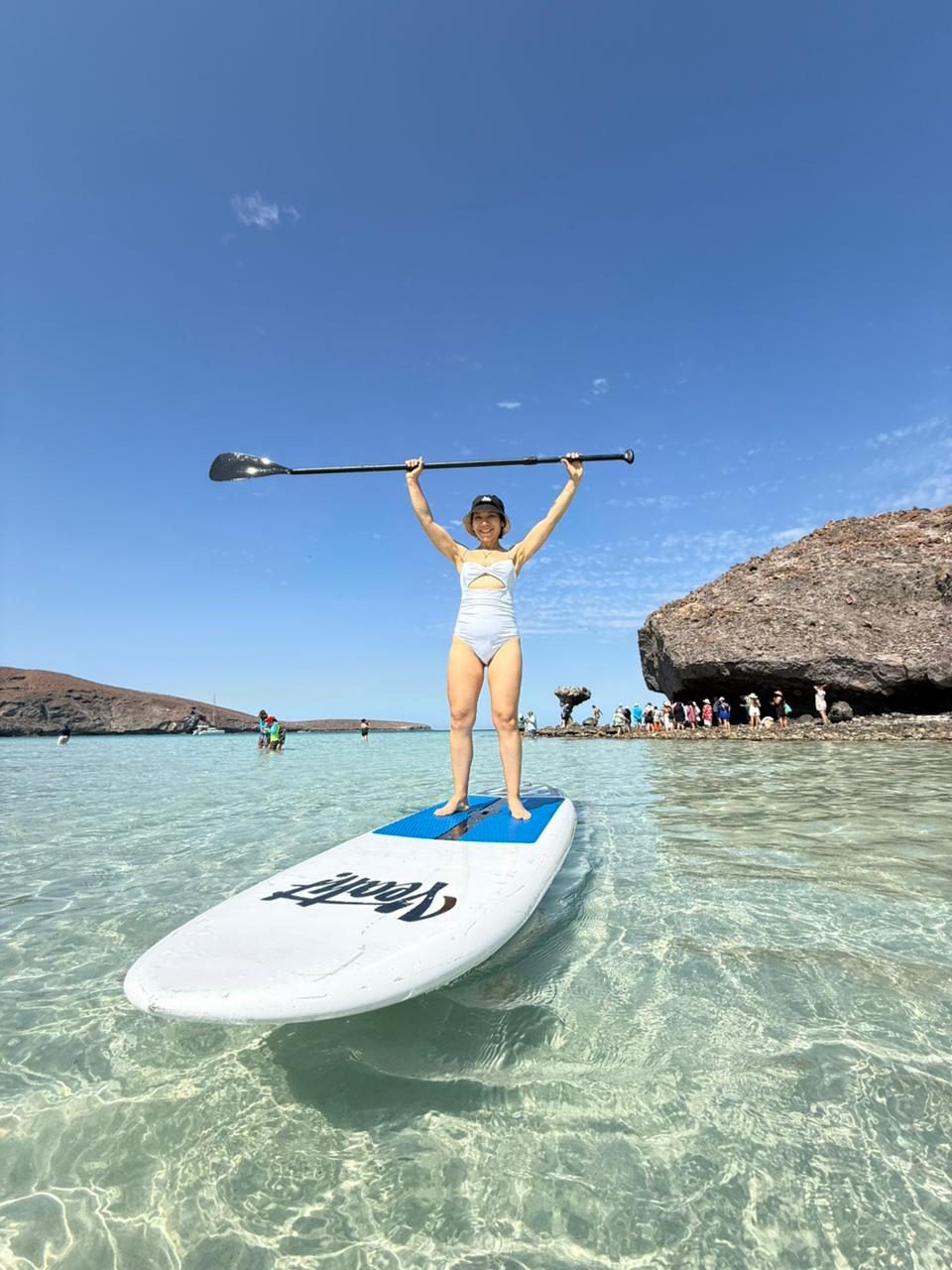 Paddleboarder de pie sobre la tabla en el agua turquesa de Tecolote